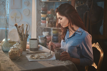 Young attractive woman is making a beautiful decorative plate at her workshop.