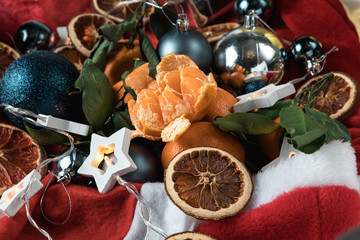 Christmas still life of citrus, pine cones and nuts, with garlands, on a red background.