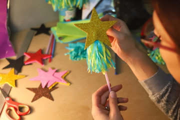 woman glues paper details on a plastic rod.  Glue, paper, scissors on a wooden table. Children's art project, a craft for children