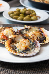 Baked scallops with cheese and spicy sauce. Delicate clam is a real pleasure. Romantic dinner at a Spanish fish restaurant. Mallorca Island, Spain.