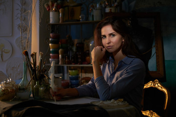 Beautiful creative woman is working on her new project at nicely decorated workshop.