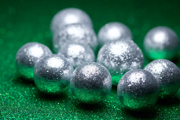 Macro abstract view of glittery silver holiday baubles on a sparkling green background