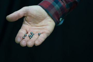 mountain bike repair. Bike mechanic in the workshop. Mechanic holds the bearing in his hand from of the bike hub. Hand and balls from the bearing close-up. A man in a fashionable plaid shirt.