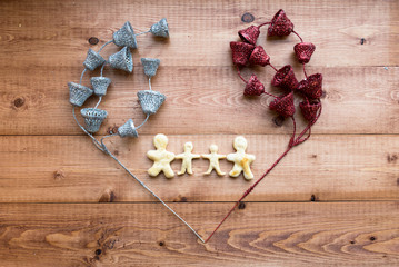 The image of a loving family. Figures of people from the dough framed by shiny jewelry on a wooden background. Valentine's Day. Selective focus. Place for text.