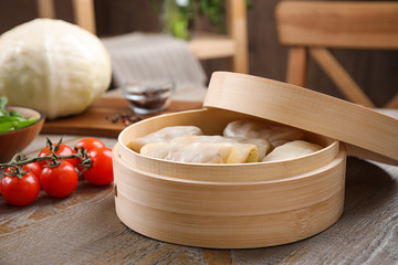 Delicious cabbage rolls in bamboo steamer on wooden table indoors