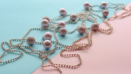 Christmas balls and garland on a blue and pink background, New Year concept. Top view.