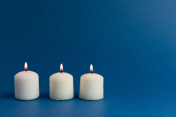 Close up of burning candles against dark blue background. Holiday concept