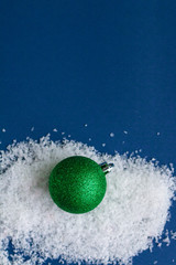 Green bright shiny Christmas ball isolated on snow, template with space for text