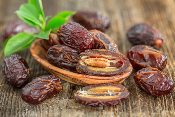 Juicy dates in a bowl on a old wooden table .