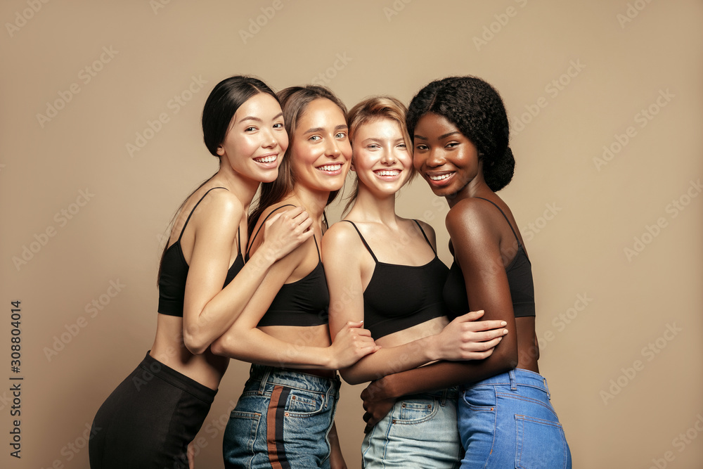 Wall mural multi ethnic group of womans with diffrent types of skin standing together and looking on camera. di