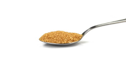Closeup pile brown sugar in a metal spoon isolated on white background.
