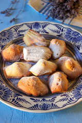 Lavender madeleines on a porcelain plate on a blue background. Rustic style.