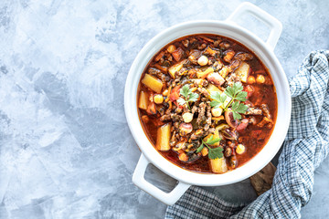 Thick minced meat soup with tomatoes, beans, chickpeas and vegetables. Healthy dinner. View from above. Copy space. top view