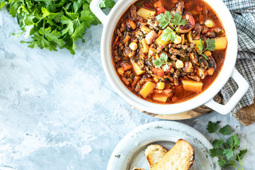Thick minced meat soup with tomatoes, beans, chickpeas and vegetables. Healthy dinner. View from above. Copy space. top view