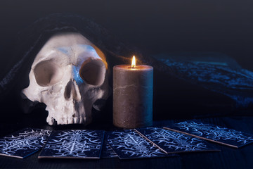 Close up of scary skull, burning candle and tarot card. Divination. Esoteric concept.