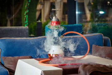 Hookah on vegetables. Hookah  flask contains chopped vegetables: pepper, cucumber, radishes, herbs. Vegetables are filled with red liquor. Bowl of red pepper hookah. Lots of smoke.