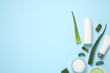Flat lay composition with aloe vera and cosmetic products on light blue background. Space for text