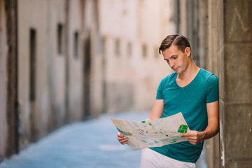 Young man with a city map in european city.