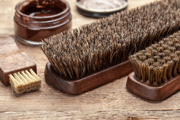 Brush for shoes. Cleaning and polishing shoes with brushes. Shoe polish and brush on wooden background