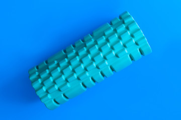 Sport green foam roller on blue background. Fitness background.