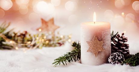 Romantic winter and christmas greeting card with text - Burning candle with natural fir and pine cone decoration on a bright background and copy space