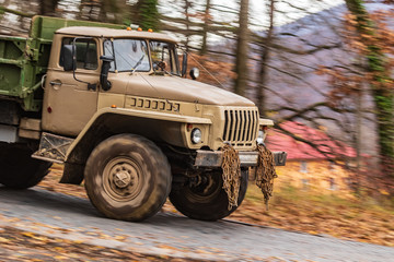 A large heavy car rushes down the mountainside. Forest mountain landscape in the fall.  Off road vehicle.