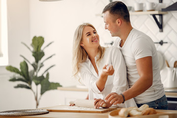 Couple in a kitchen. Blonde in a white shirt. Woman with her husband