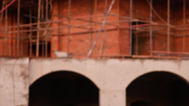 Construction of church building. Fencing with red warning lights. Scaffolding and red brick masonry. Concreting arched vaults. Workers tie rebar
