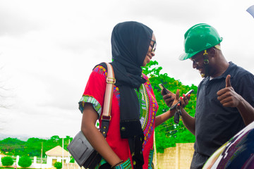 Obraz premium Young African man making a contactless payment with a beautiful woman after fixing a car