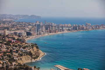 Beautiful super wide-angle aerial view of Calpe, Calp, Spain with harbor and skyline, Penon de Ifach mountain, beach and scenery beyond the city, seen from Mirador Monte Toix mountain viewpoint