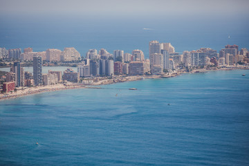 Obraz premium Beautiful super wide-angle aerial view of Calpe, Calp, Spain with harbor and skyline, Penon de Ifach mountain, beach and scenery beyond the city, seen from Mirador Monte Toix mountain viewpoint