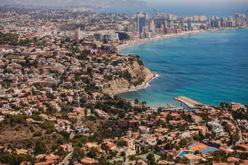 Beautiful super wide-angle aerial view of Calpe, Calp, Spain with harbor and skyline, Penon de Ifach mountain, beach and scenery beyond the city, seen from Mirador Monte Toix mountain viewpoint