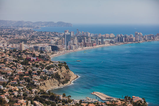 Beautiful super wide-angle aerial view of Calpe, Calp, Spain with harbor and skyline, Penon de Ifach mountain, beach and scenery beyond the city, seen from Mirador Monte Toix mountain viewpoint