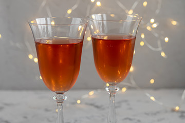 Orange wine is poured into two glasses. Celebratory drink. Family celebration.
