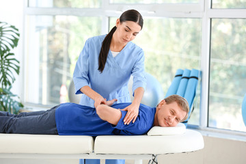 Fototapeta premium Physiotherapist working with male patient in rehabilitation center