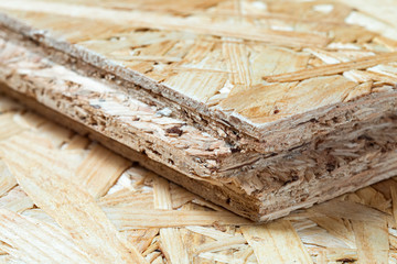 Detail of tongue and groove chip board lying on top of chip board. Blurred background.