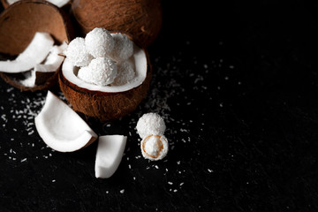 cooked coconut milk candies on a black dark background, ingredients for a dessert with coconuts, a sweet product with coconut flakes
