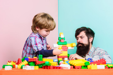 Surefire ways to bond with your son. Dad and kid build plastic blocks. Child care development and upbringing. Father son game. Father and son create constructions. Bearded man and son play together