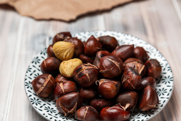 Roasted chestnuts on a plate on a wooden background