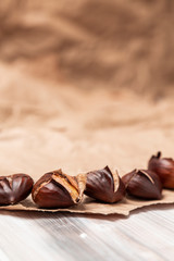 Roasted chestnuts on paper on a wooden background