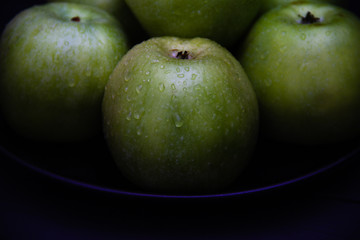 Green apples with water drops on black background.