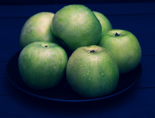 Green apples with water drops on black background.