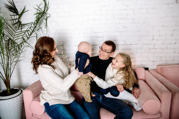 Cheerful family at home sitting in sofa. Parental love, upbringing and care. brother and sister together. Mom and Dad are nearby