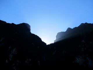 Fototapeta na wymiar Ethereal lighting (light rays) with the sun behind the silhouette of the limestone mountain range at the Khao Sok National Park, Thailand