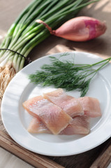 Sliced Herring Fish Fillet on White Plate. Dill and Onion