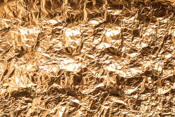Crumpled gold foil as background, top view