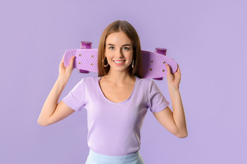 Stylish hipster girl with skateboard on color background