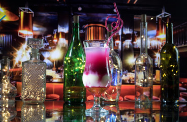 Fototapeta na wymiar Cocktail glass splashing on dark toned smoky background or colorful cocktail in glass. Party club entertainment. Mixed light. Selective focus