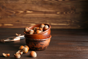 Bowl with tasty hazelnuts on wooden background