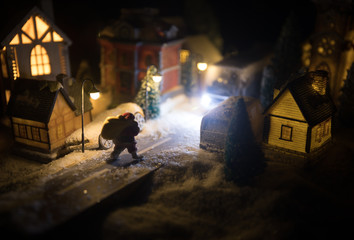 New Year miniature house in the snow at night with fir tree. Holiday concept. Selective focus